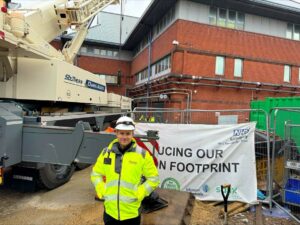 A man in high viz jacker standing in front of a construction site displaying the banner.