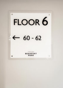 Wayfinding Signage on a white wall, directing to flats 60-62 on floor 6